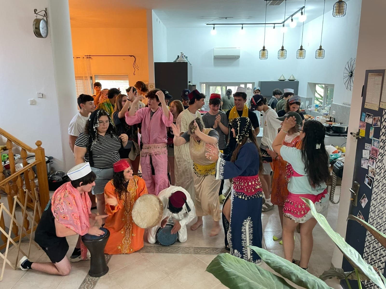 קבוצת אורחים בתלבושות פרסיות מסורתיות רוקדים ומנגנים בדרבוקות באירוח של לילי