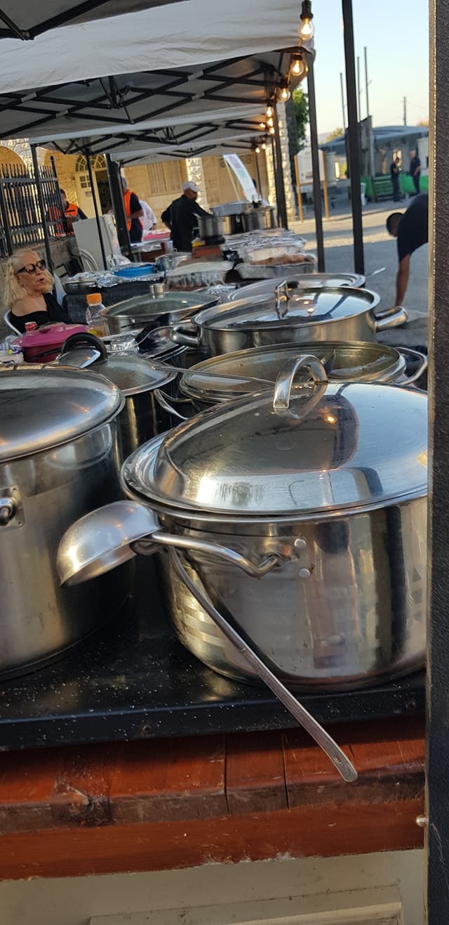 Guests seated along the Bishulilim pergola table mid-meal, smiling toward the camera