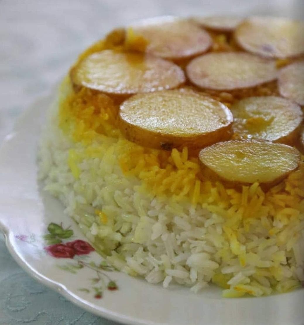 אורז פרסי עם תחדיג תפוחי אדמה זהוב, מוגש על צלחת עתיקה עם שושנים