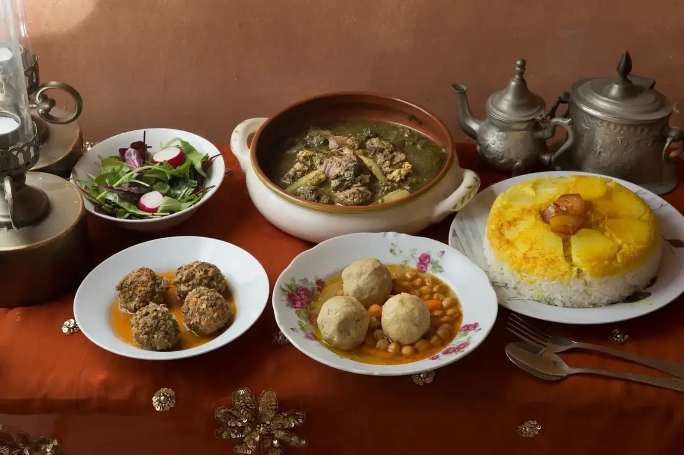 שולחן פרסי-יהודי מסודר אצל לילי — חורשט סבזי בקערת חרס, קציצות, גונדי בצלחת פרחונית, פולו עם תחדיג, סלט, ופמוטים פרסיים